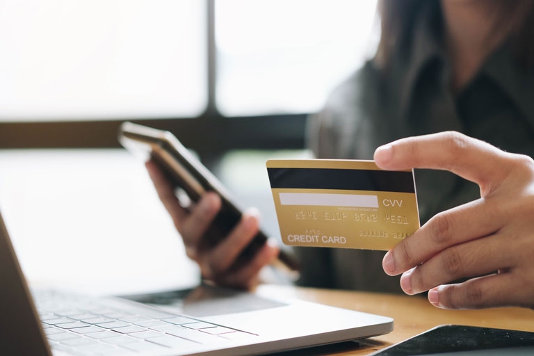 Mujer con una tarjeta de crédito haciendo una compra en línea