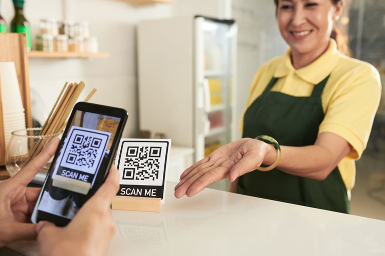 Mujer escaneando un codigo QR de pago en un restaurante
