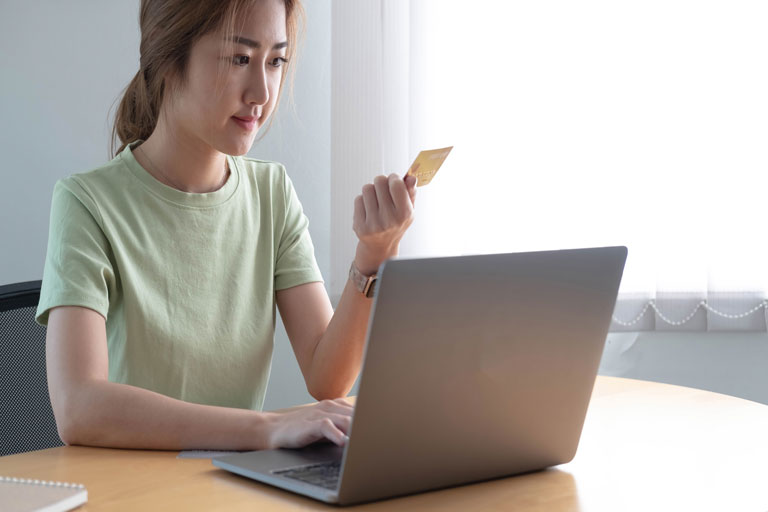 Mujer revisando los números de su tarjeta de crédito para hacer una compra en linea