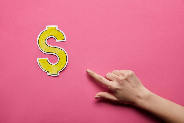 Mano de una mujer tocando con su dedo un recorte de papel con el simbolo de dinero